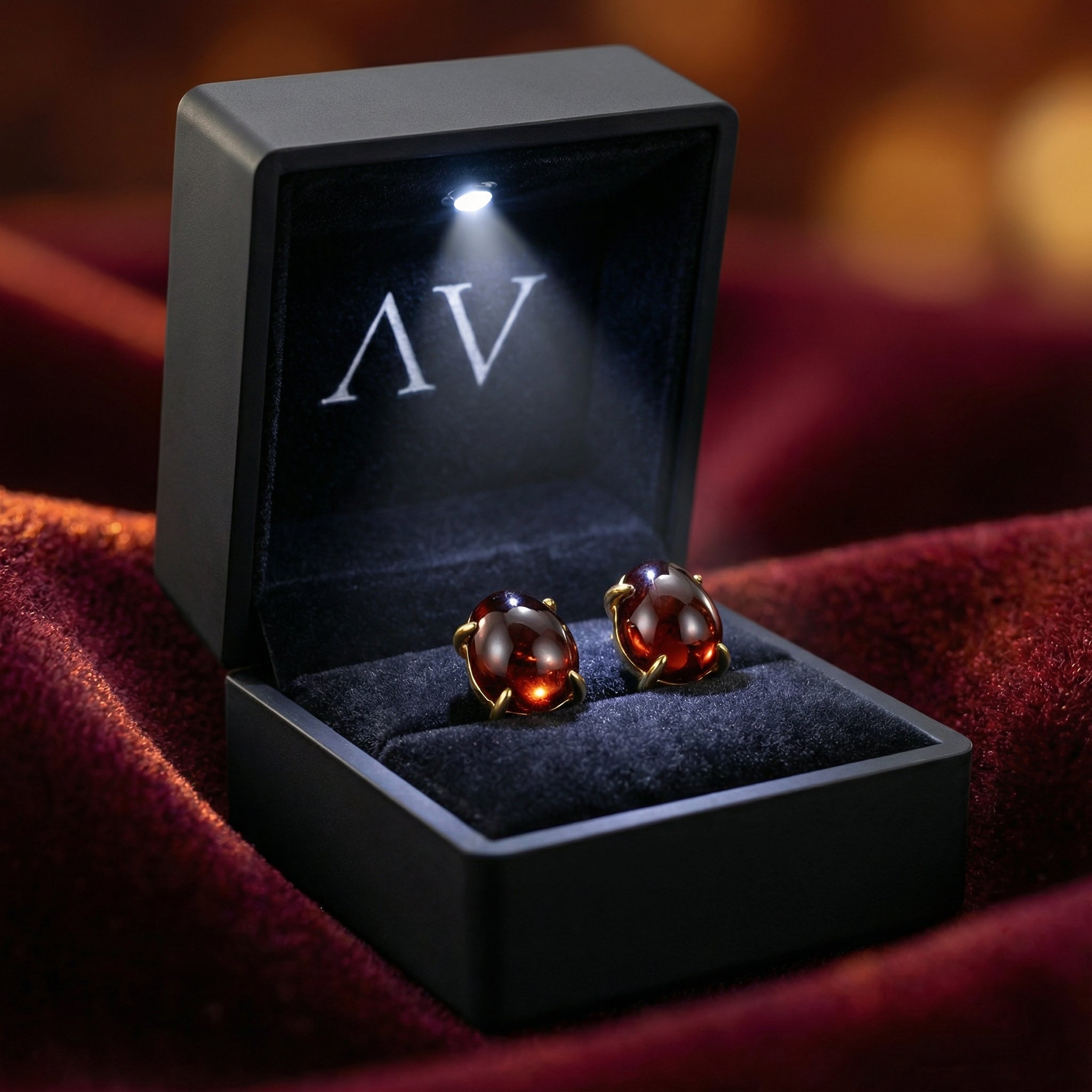 Seraphine simulated garnet stud earrings in 18K gold vermeil inside a black LED-lighted jewelry box.