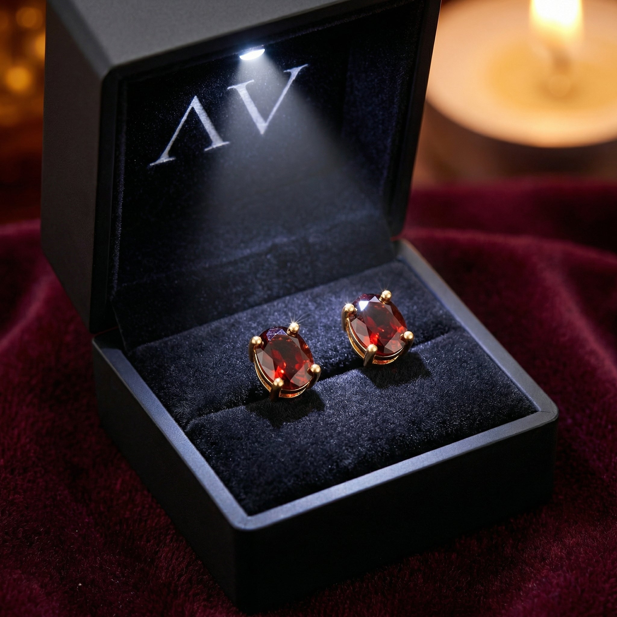 Oval cut simulated garnet stud earrings in 18K gold vermeil inside a black LED-lit jewelry presentation box.