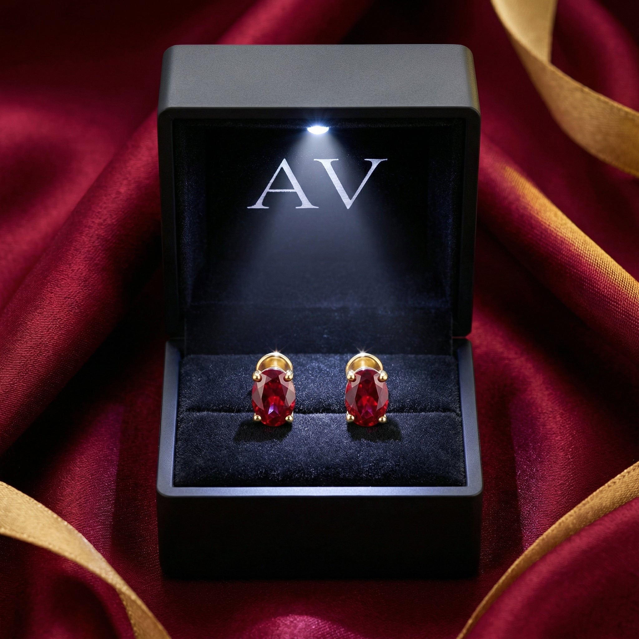 Oval simulated ruby earrings in 18K gold vermeil displayed in a black LED-lit jewelry box.