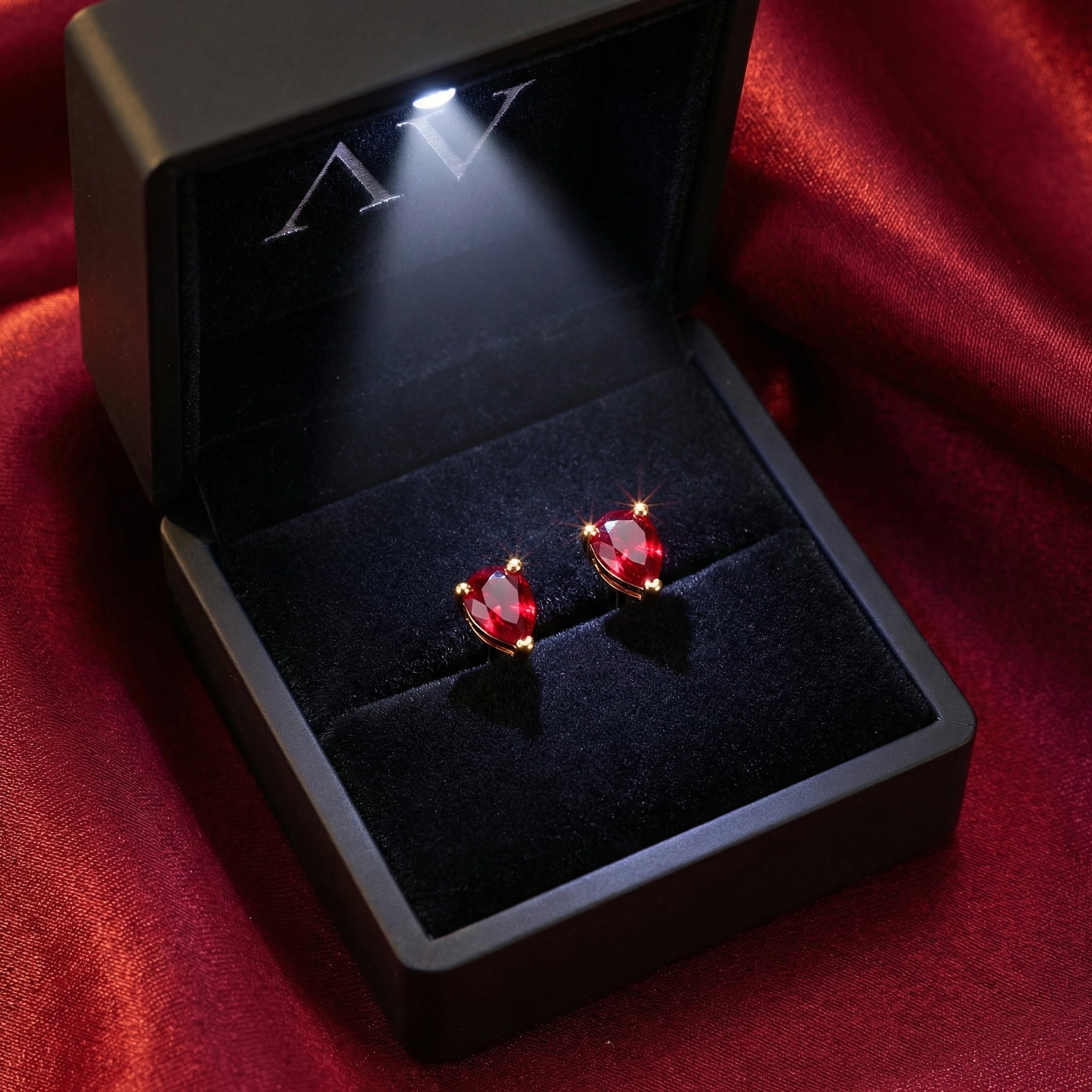 Pear cut simulated ruby earrings in 18K gold vermeil inside a lighted black jewelry gift box.