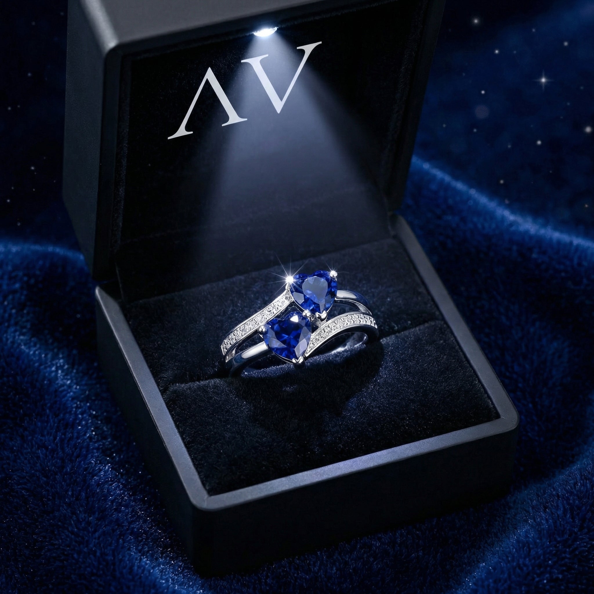 The Marineza heart ring with blue sapphires inside a lighted black velvet gift box on a blue background.