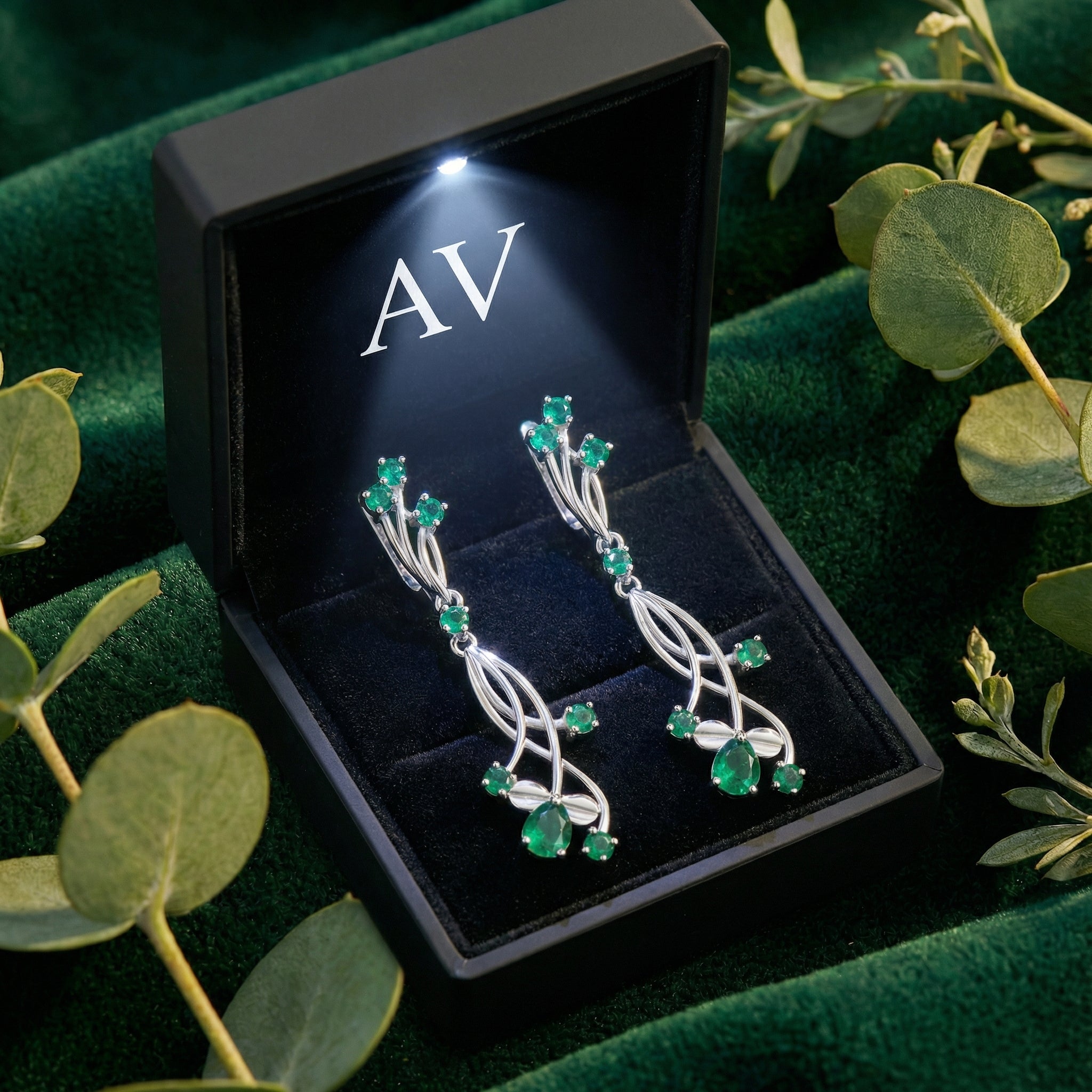 Calysia Vine sterling silver pear and round cut simulated emerald drop earrings in a lighted black jewelry box.