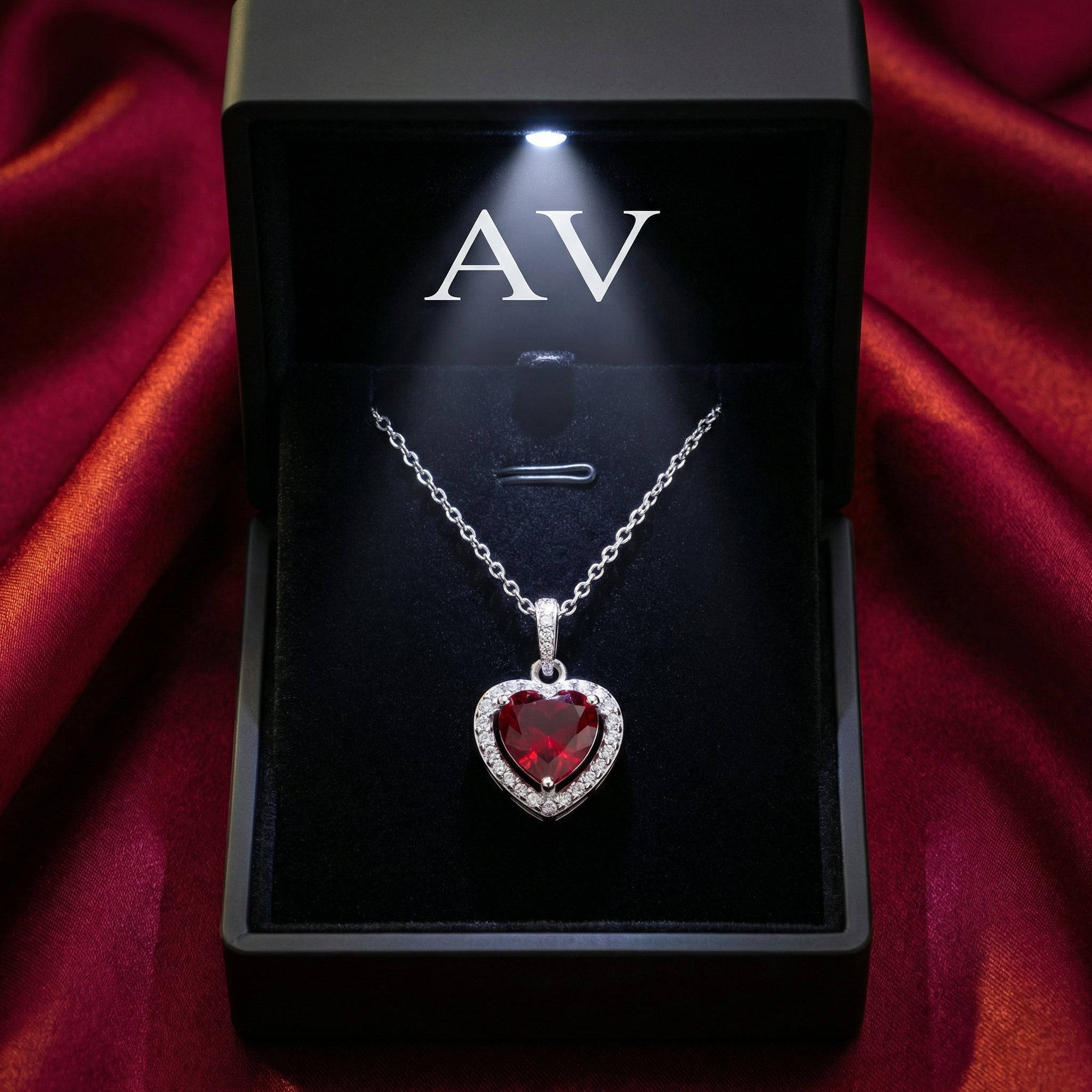 Heart-cut simulated ruby necklace in a black LED-lit jewelry box on a red satin background.