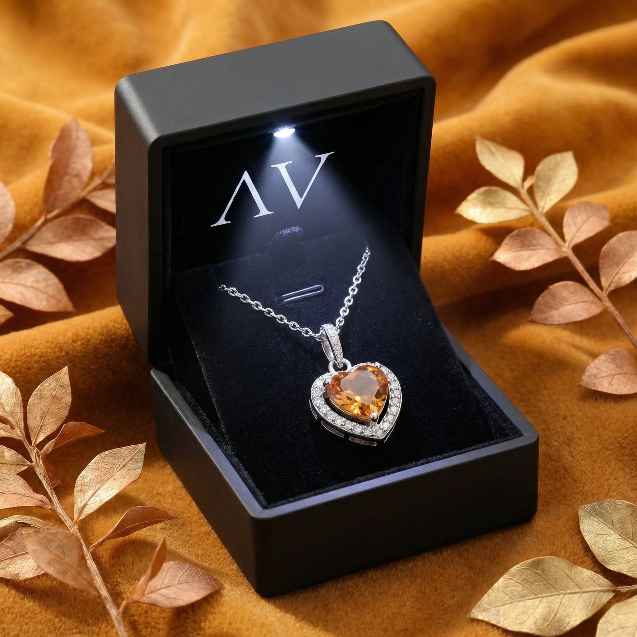 Heart-shaped simulated topaz necklace in a lighted black jewelry gift box on golden velvet.