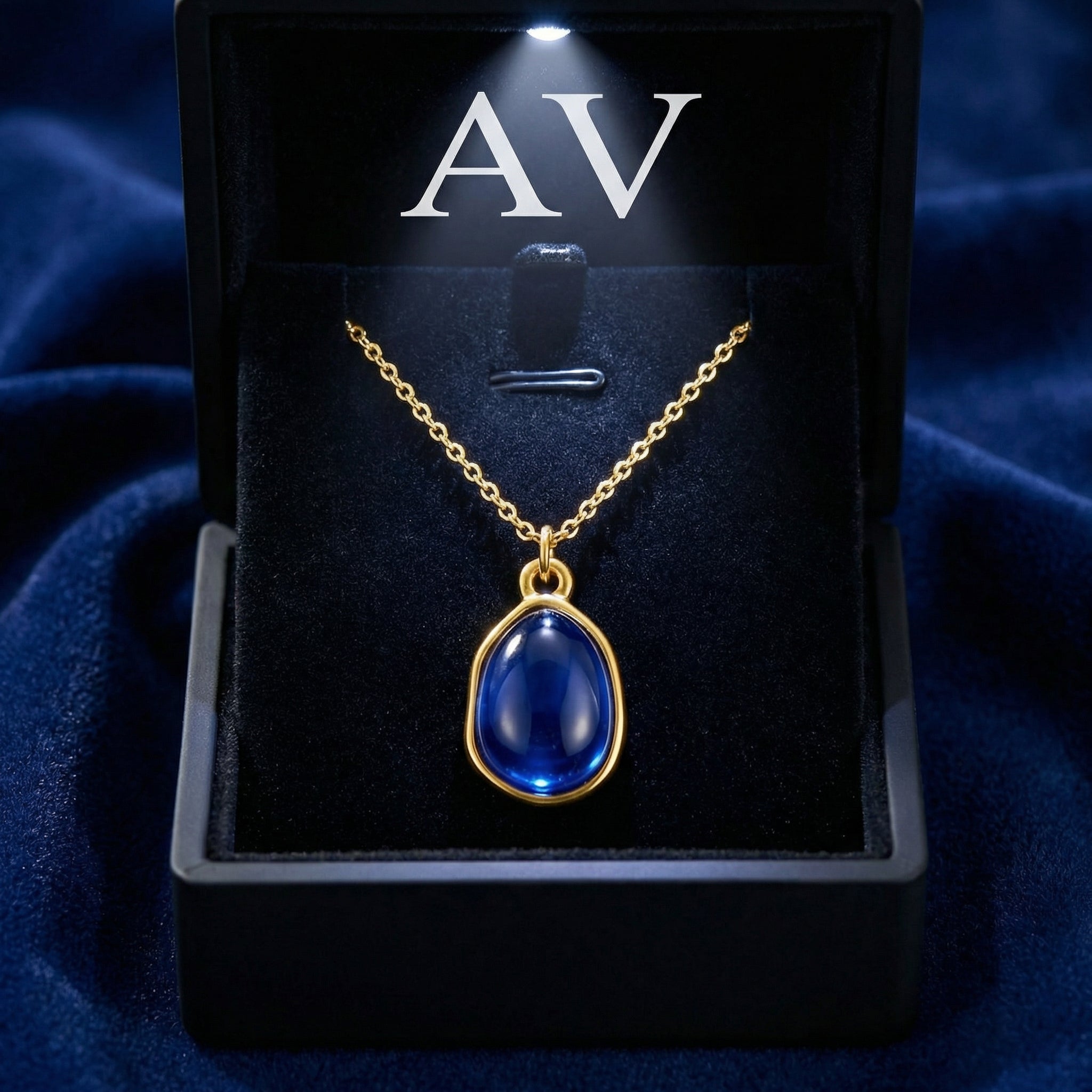Gold-finished stainless steel Mariselle simulated sapphire teardrop necklace in a black lighted jewelry box with AV branding.