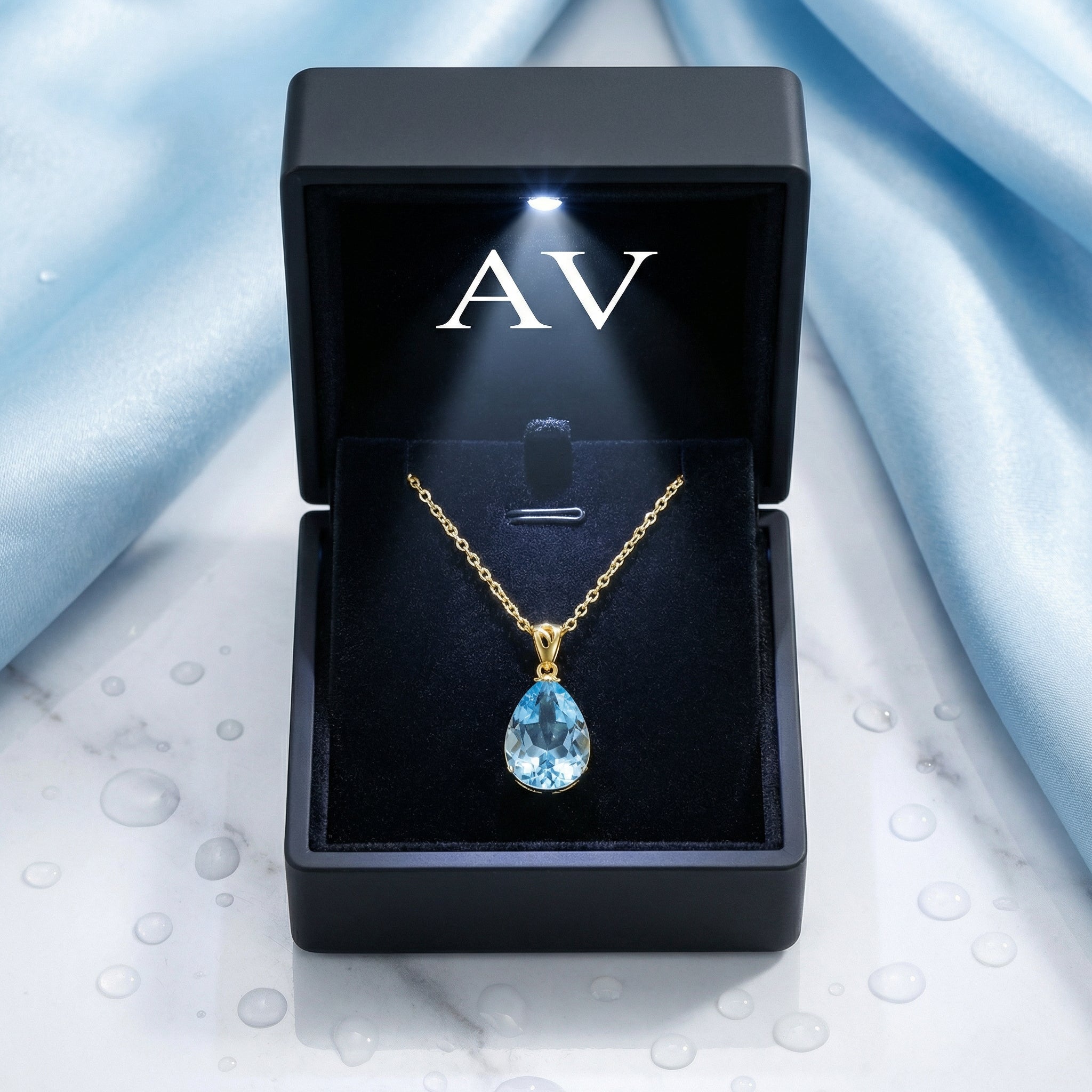 Pear cut simulated aquamarine necklace in 18K gold vermeil inside a black lighted jewelry gift box.