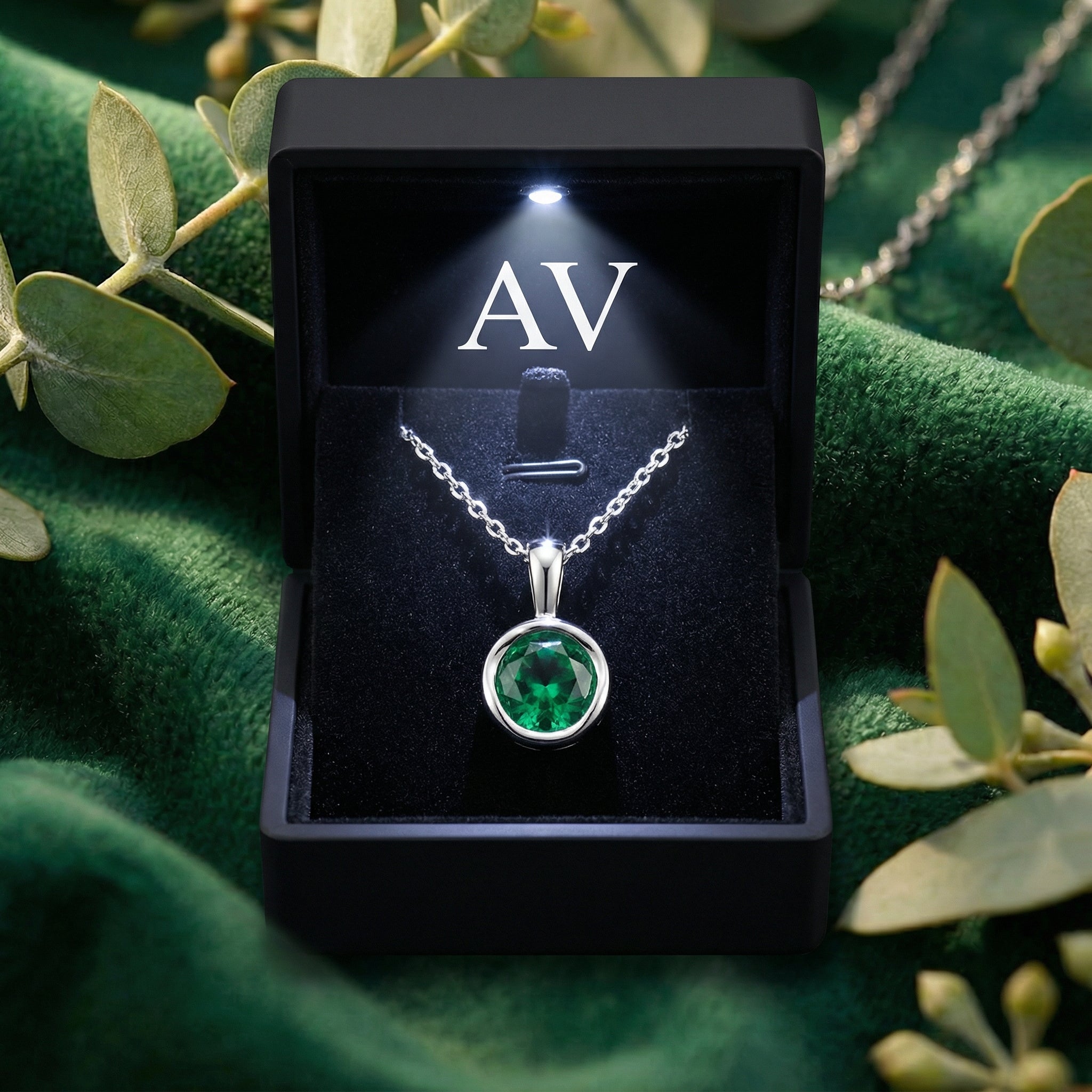Simulated emerald bezel necklace in a black lighted gift box with AV branding on green velvet.