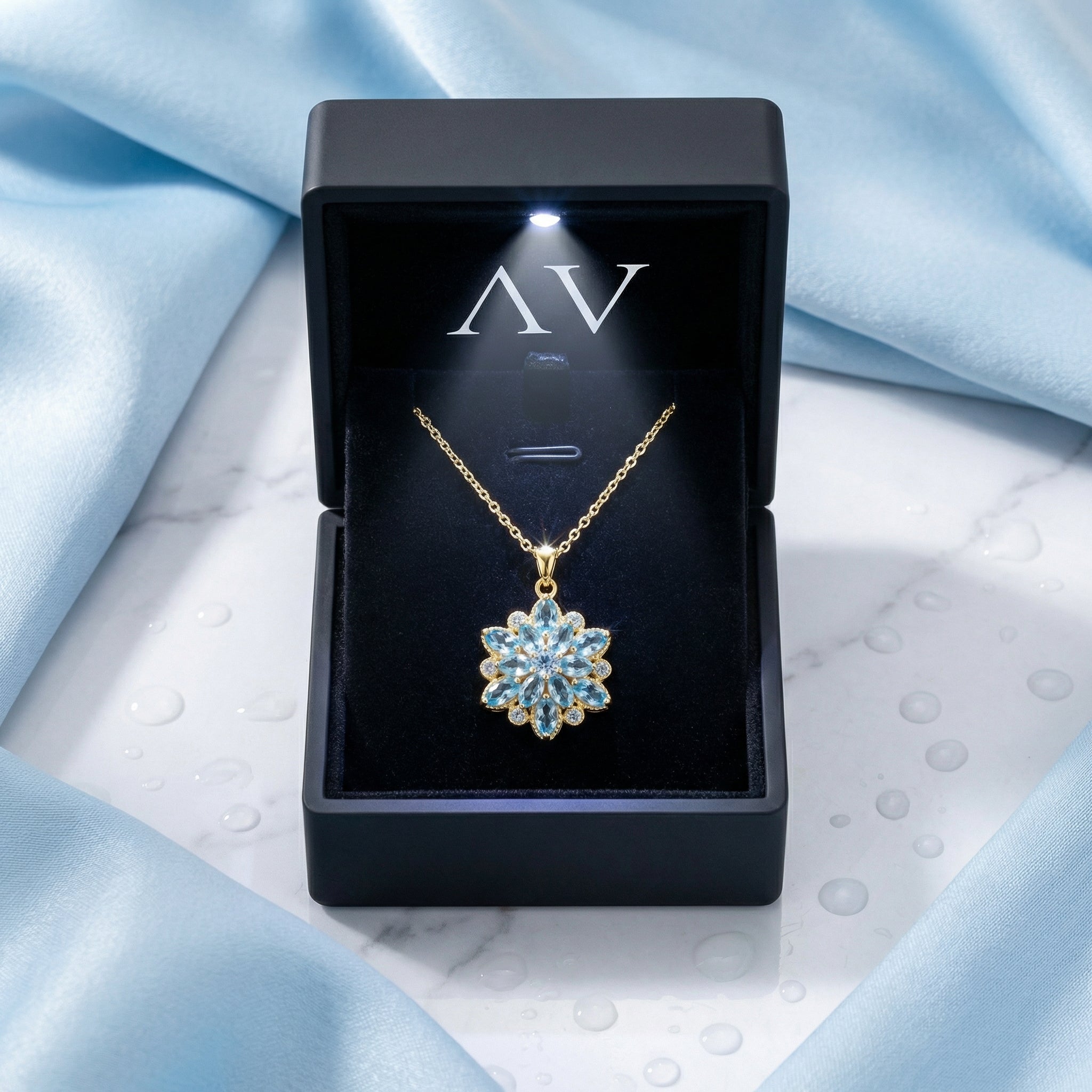 Gold stainless steel simulated aquamarine flower necklace inside a black LED-lighted jewelry presentation box.