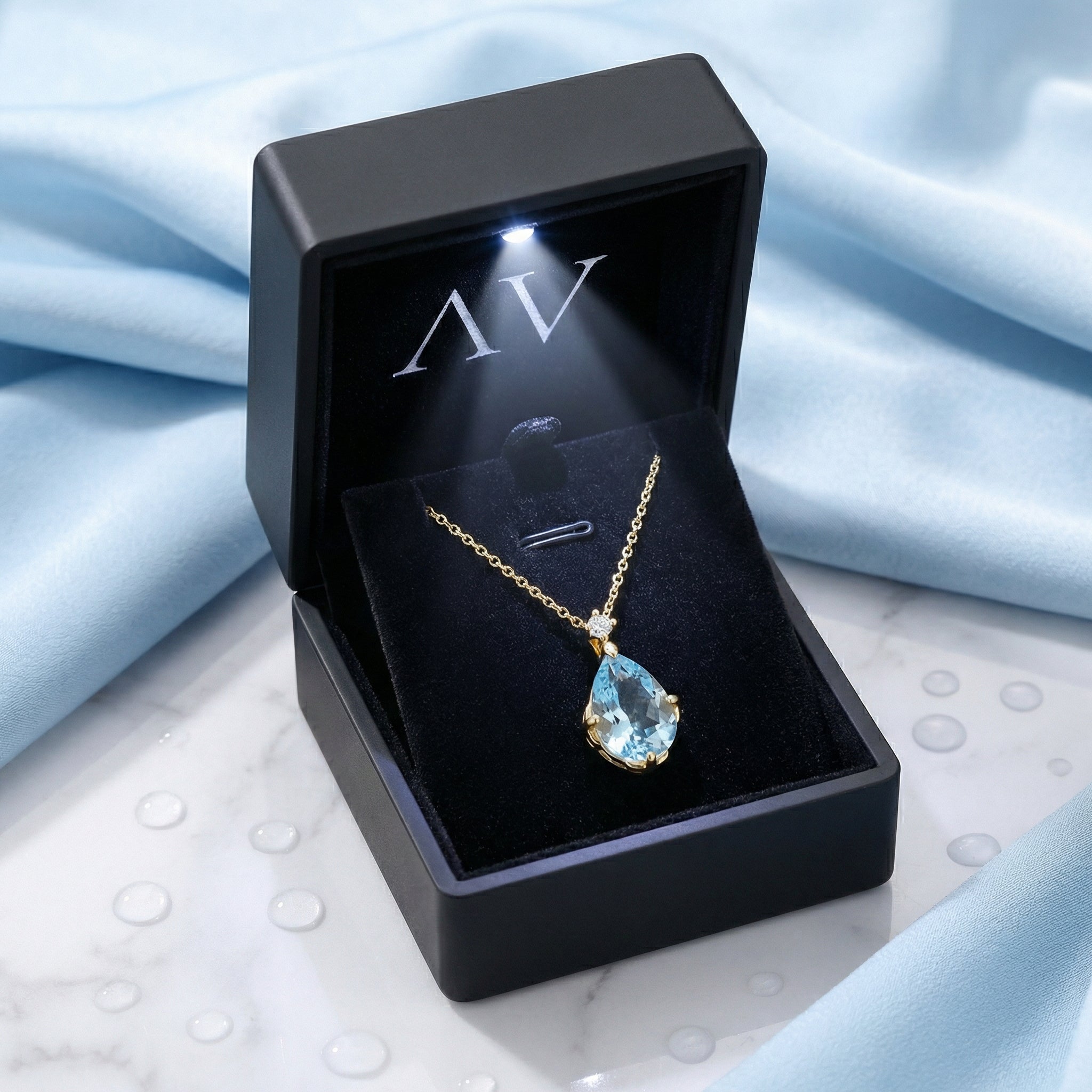 Pear cut simulated aquamarine necklace in 18K gold vermeil presented in a lighted black jewelry box.