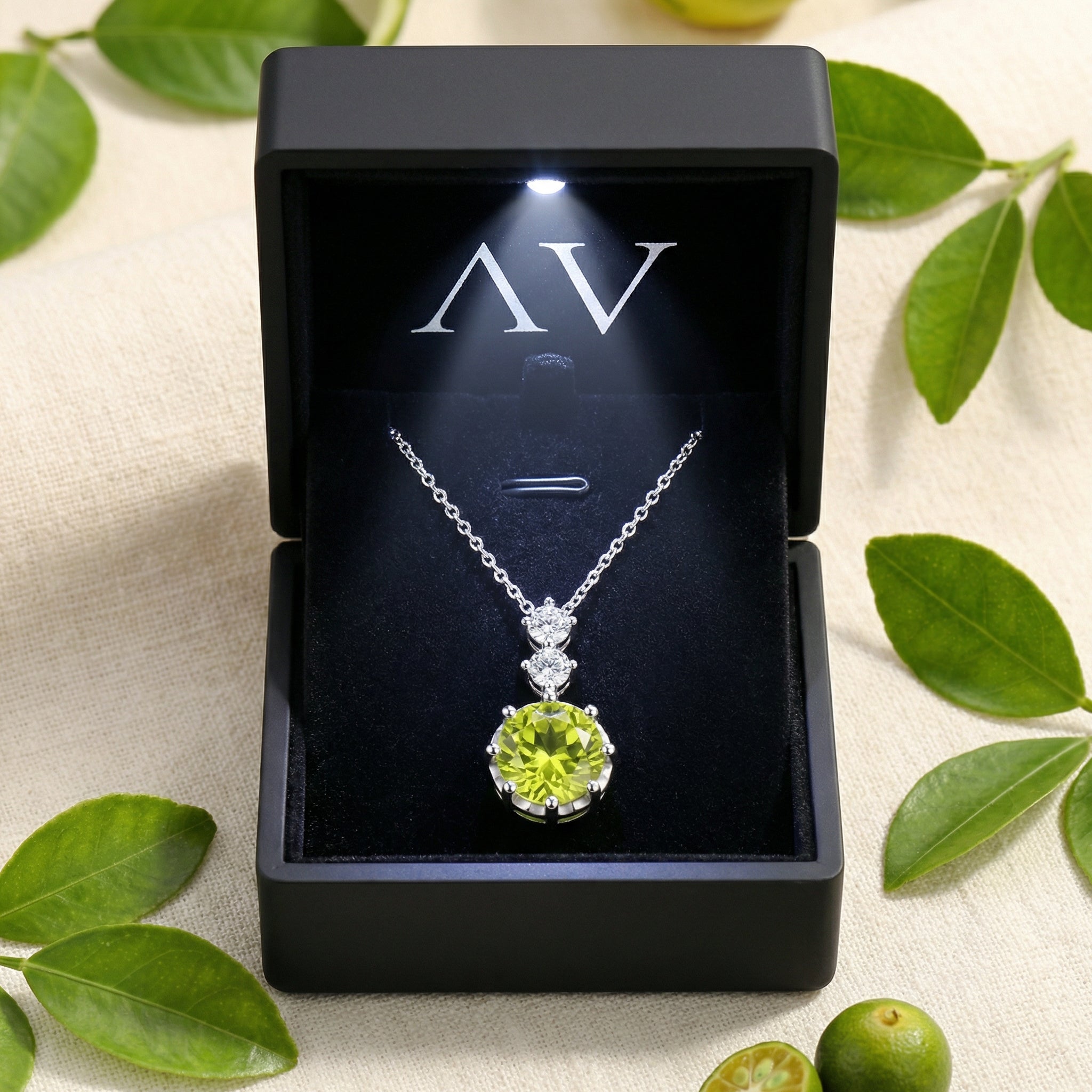 Simulated peridot necklace inside a lighted black jewelry box with an AV logo, styled with leaves.