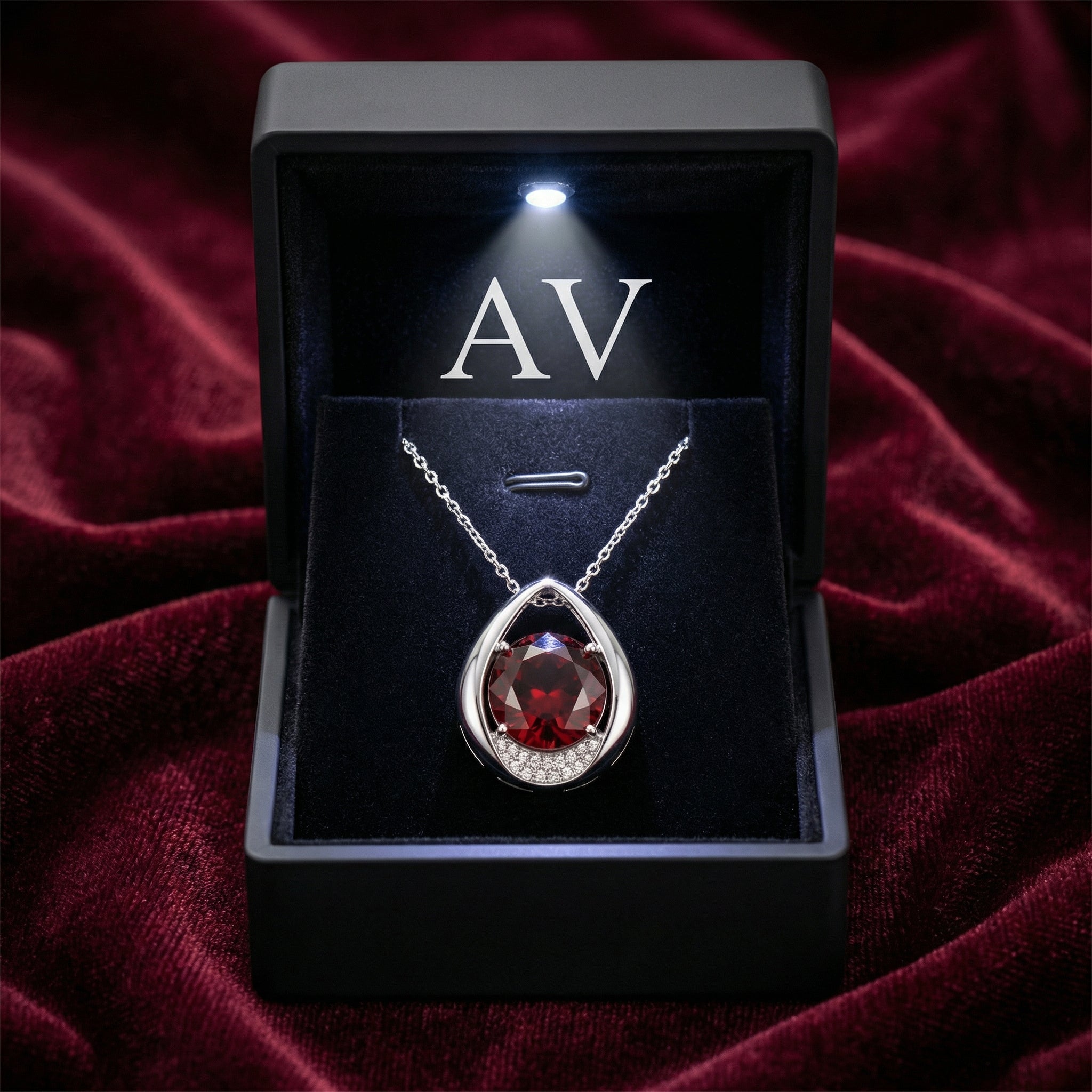 Front view of the sterling silver simulated garnet teardrop necklace inside an illuminated black jewelry box.