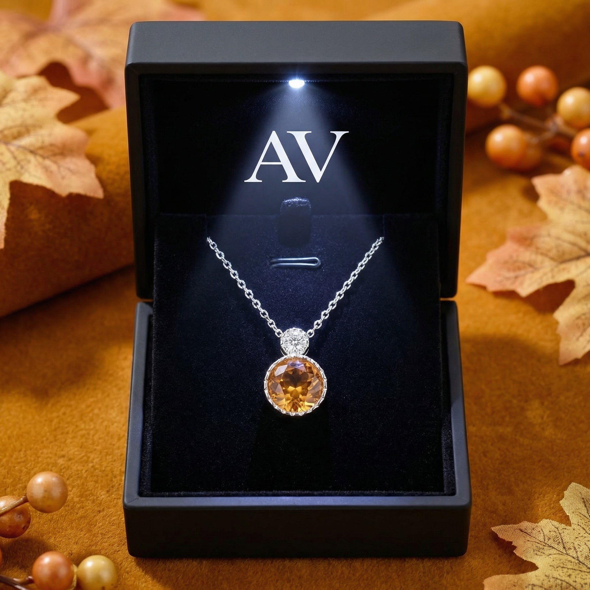 Simulated topaz sterling silver necklace presented in a black lighted jewelry box with autumn leaf accents.
