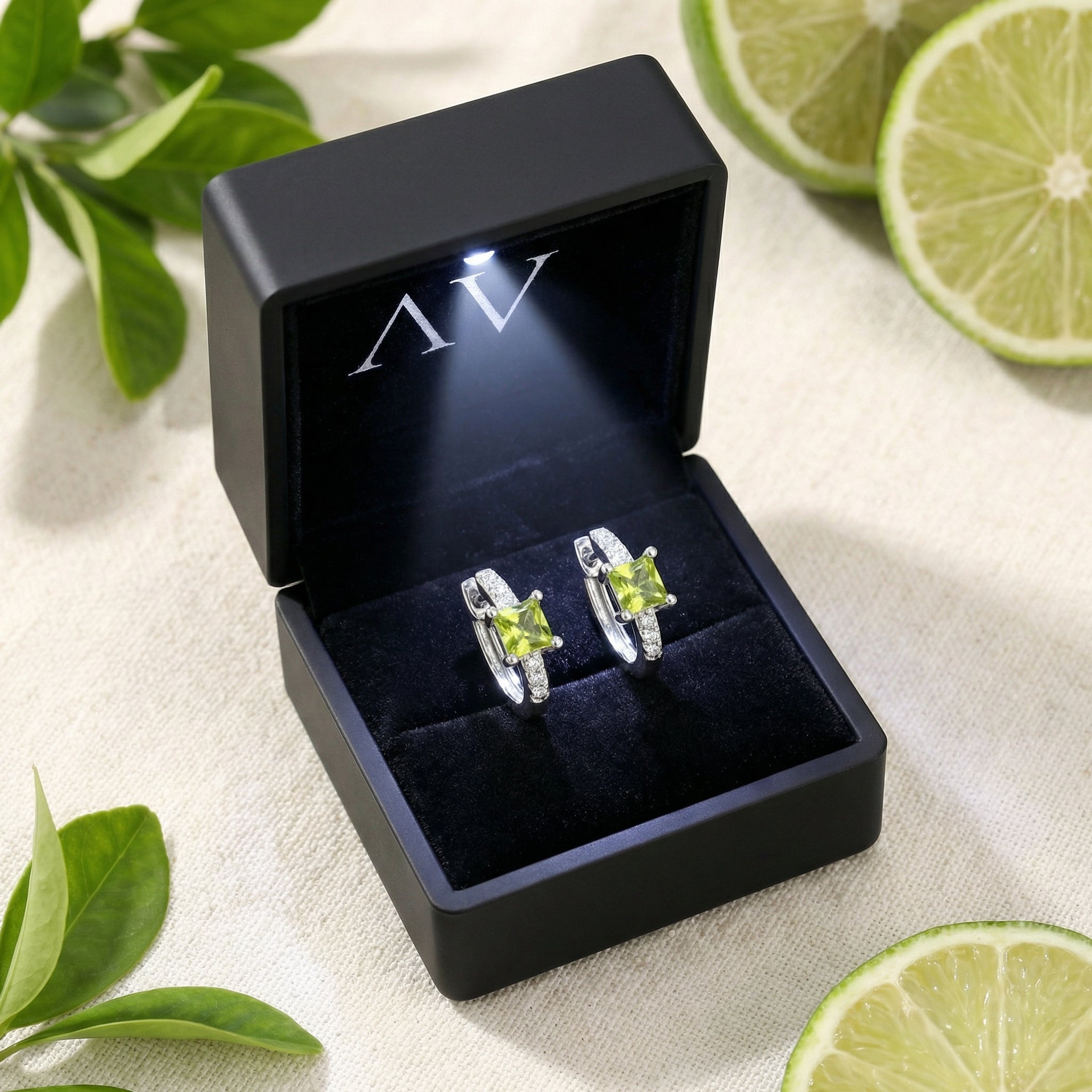 Square-cut simulated peridot sterling silver earrings inside a black LED-lit jewelry presentation box.