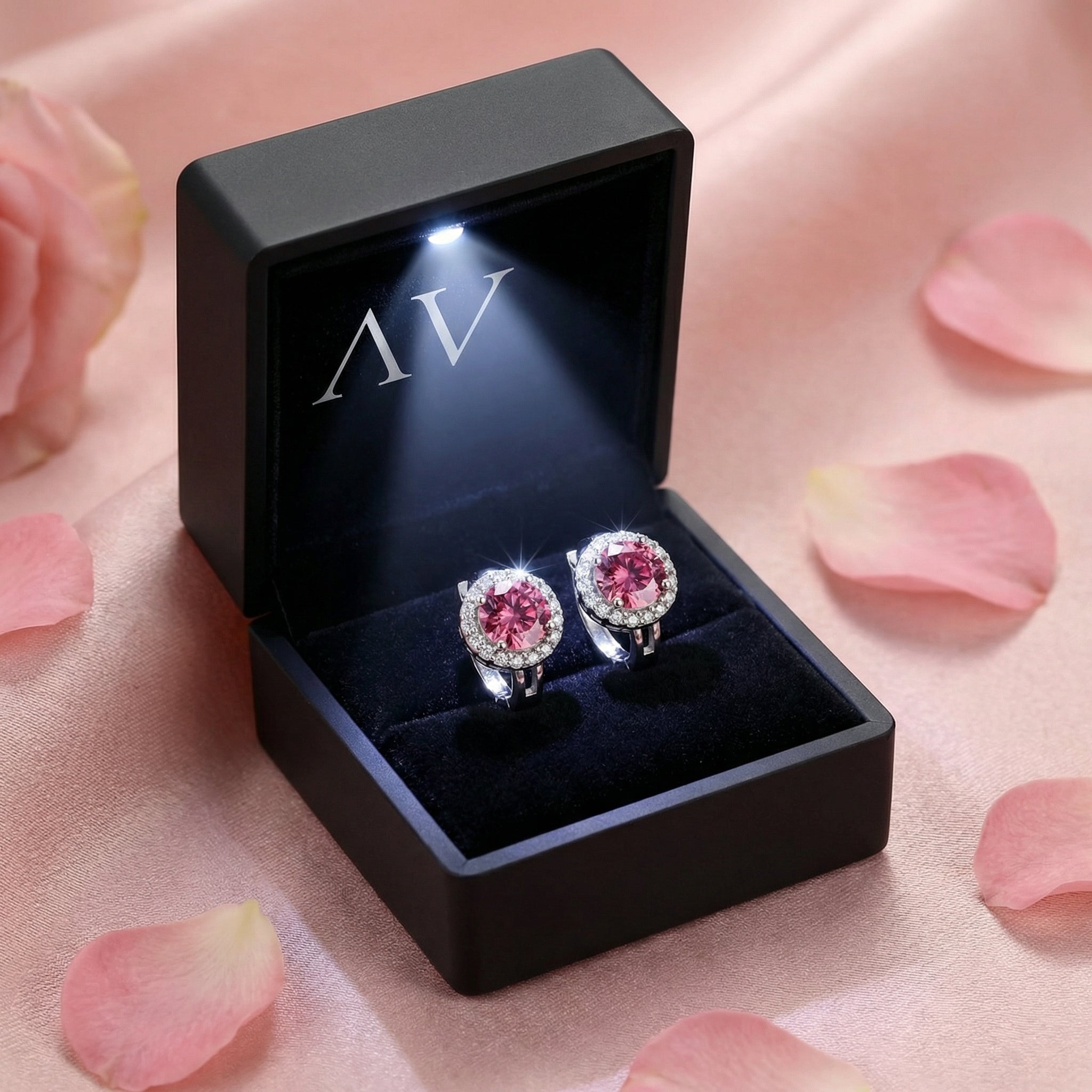 Pink moissanite halo stud earrings in sterling silver inside a black LED-lit jewelry gift box.