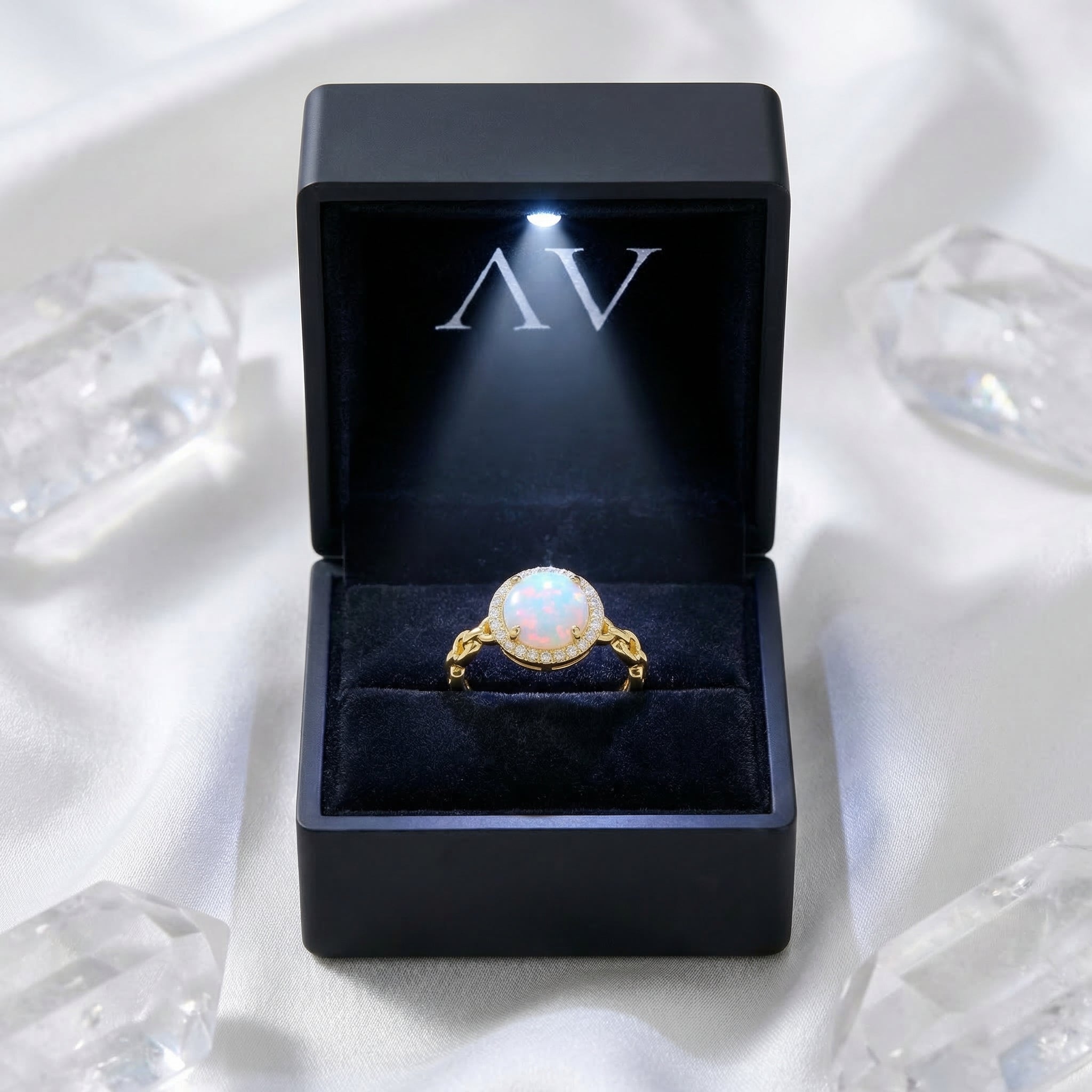 Gold-tone natural white opal ring presented in a black LED-lighted jewelry box on a white silk background.
