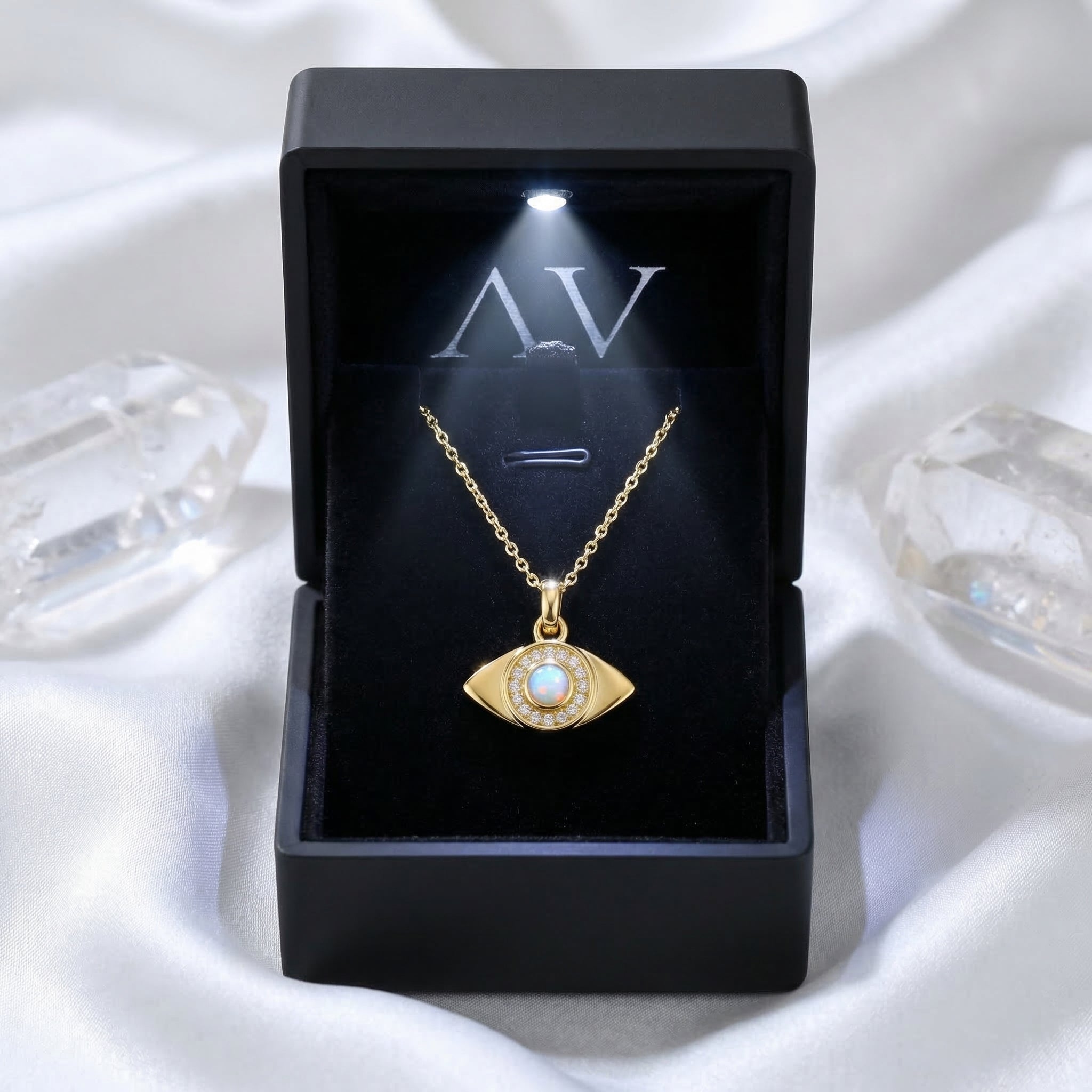 Gold white opal evil eye pendant necklace inside a black lighted jewelry gift box on white silk.