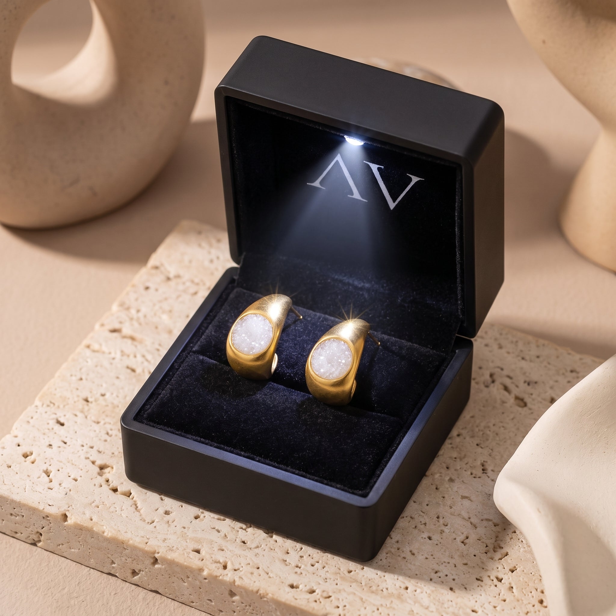 Gold white quartz druzy earrings in black LED-lit jewelry box.
