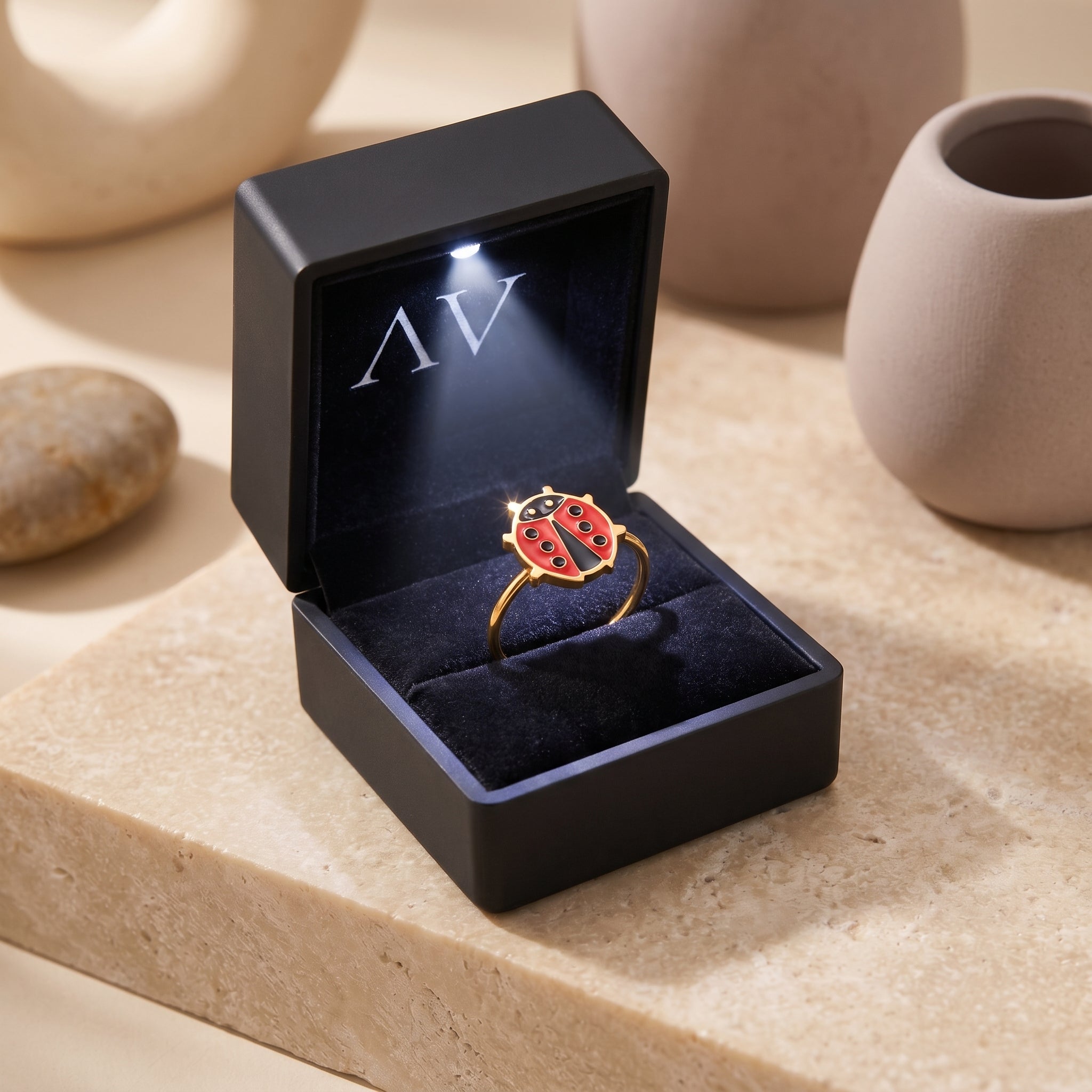 Gold ladybug ring inside a black LED-lit gift box.