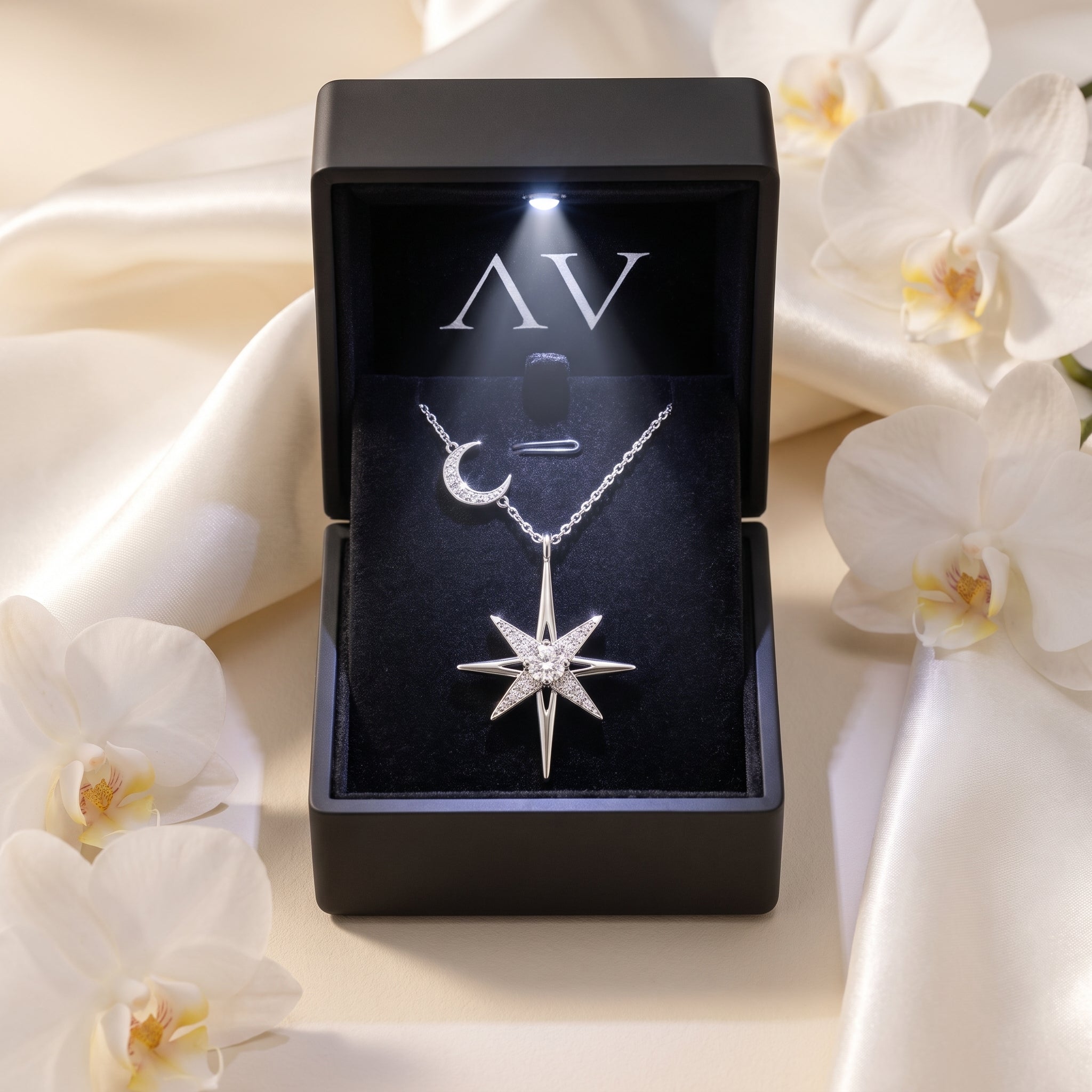 Silver moissanite starburst necklace presented in a lighted black gift box with white orchids.