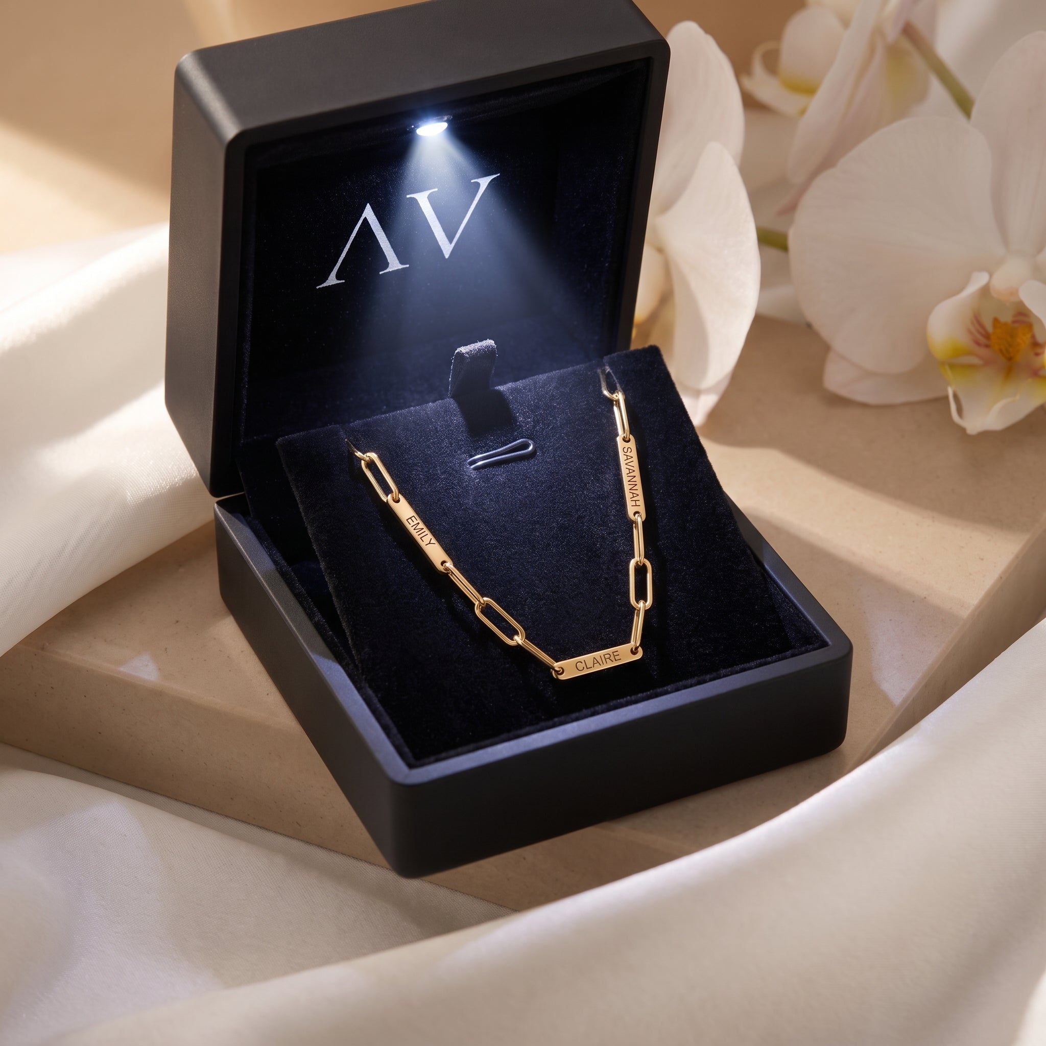 Gold stainless steel paperclip name necklace in black LED-lit gift box.