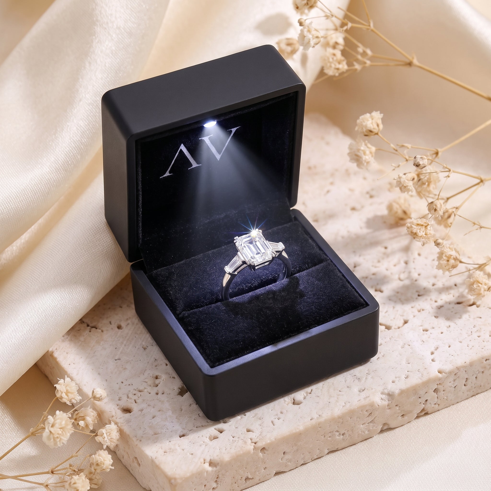 Emerald cut silver ring inside a black LED-lit jewelry presentation box.