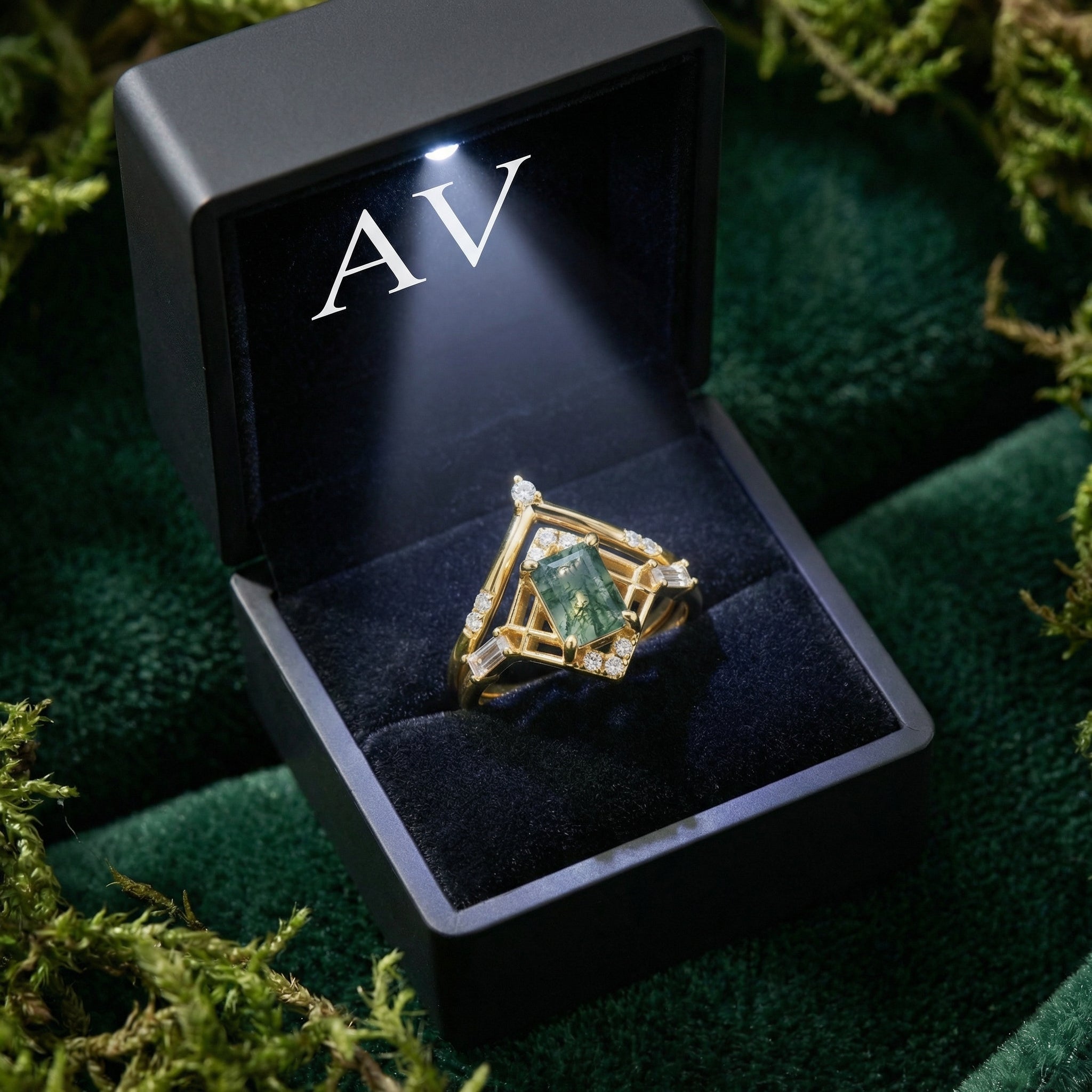 Gold-plated moss agate ring set presented in a black LED-lit gift box on a bed of moss.