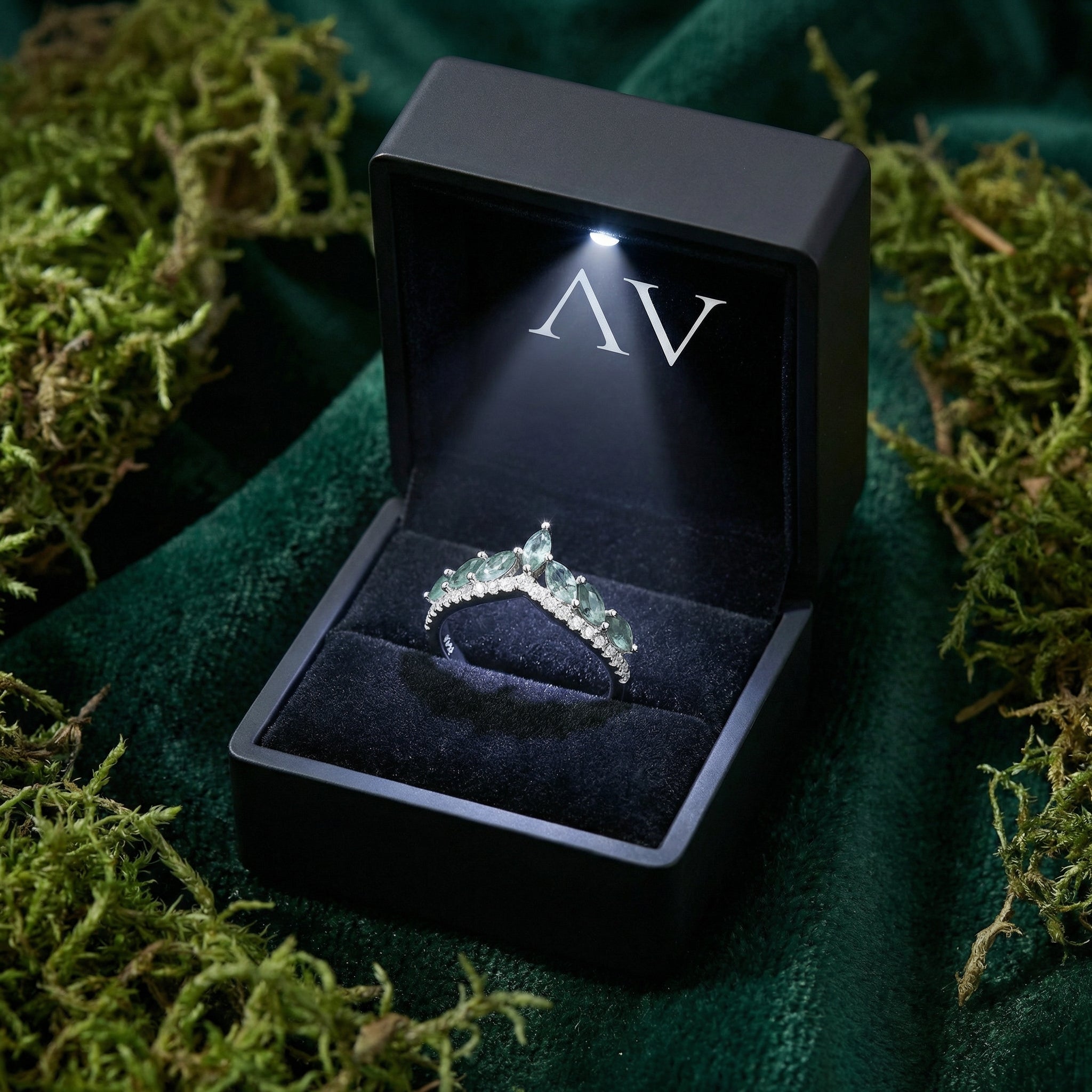 Moss agate and diamond wave ring presented in a black LED-lighted gift box on green velvet and moss.