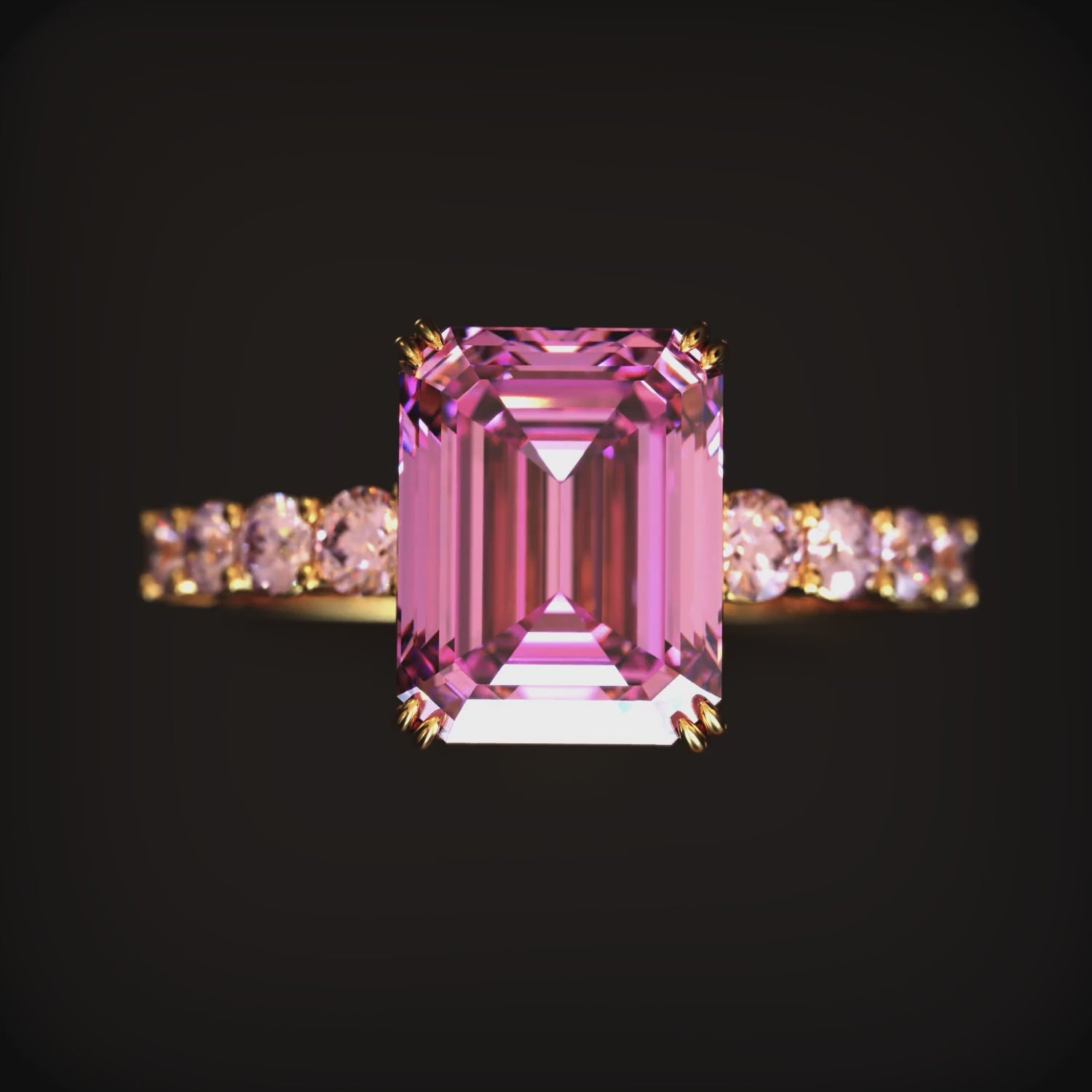 A ring with an emerald-cut pink moissanite stone in solid gold