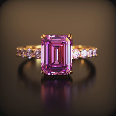 A ring with an emerald-cut pink moissanite stone in solid gold