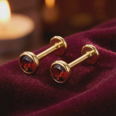 Close-up showcase of precision-cut simulated garnet stud earrings in solid gold.