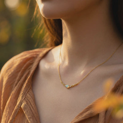 Model wearing a solid gold necklace featuring an iridescent white opal pendant.