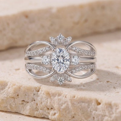 Front view of a sterling silver ring with an oval center stone, curved pavé bands, and floral clusters on beige stone.