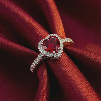 A solid gold ring with a heart-shaped simulated ruby.