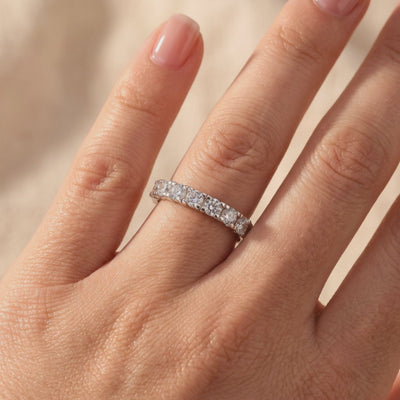 Evadienne silver eternity ring with round clear stones worn on a finger in close-up