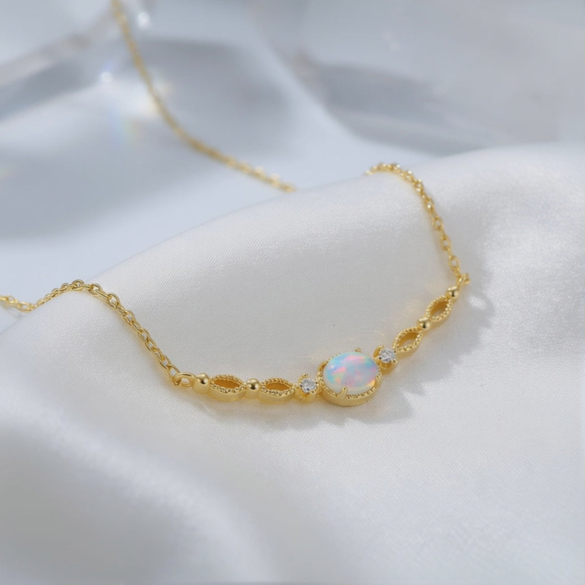 Detailed view of a solid gold white opal pendant and chain resting on white satin.