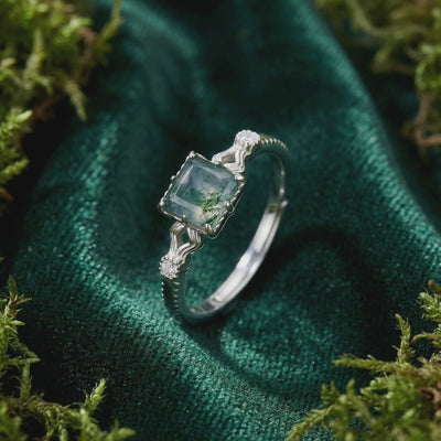 A solid gold cushion cut natural moss agate ring with a wavy band.