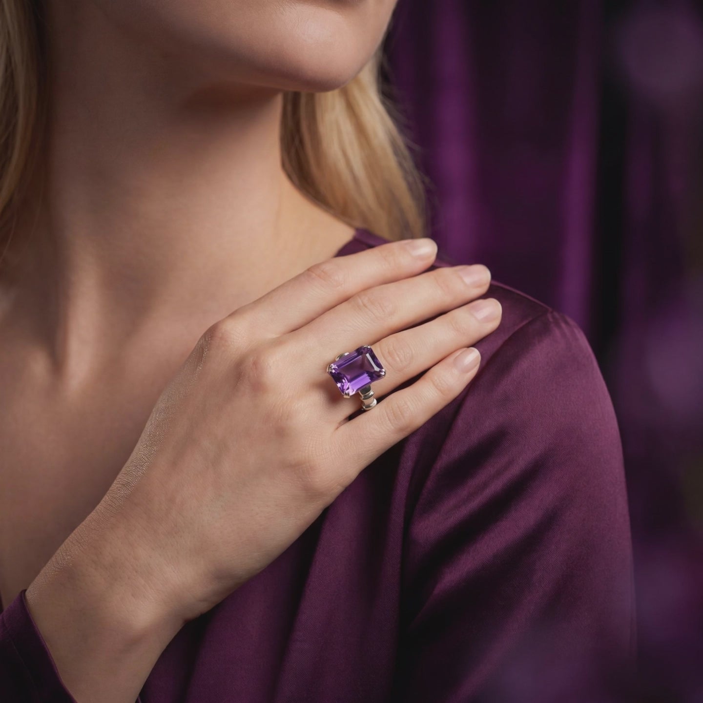 Model wearing an emerald-cut violet amethyst ring in a polished white-metal setting.