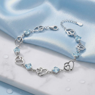 Detailed view of The Caelia Heart solid gold bracelet showcasing its light blue simulated aquamarine stones.