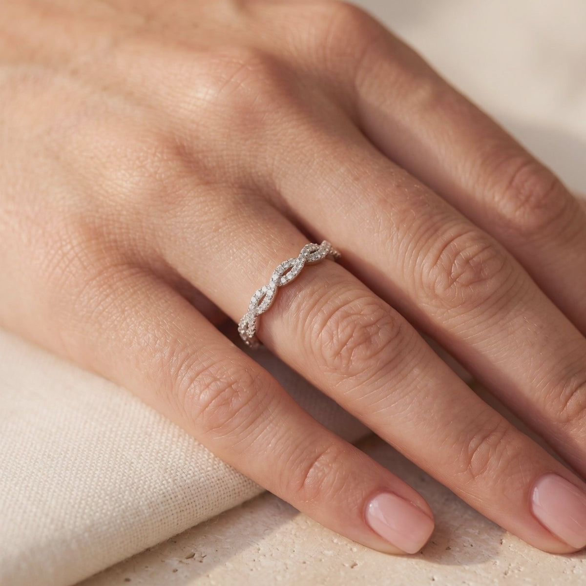 Silver twisted eternity ring with clear pavé stones worn on a finger.