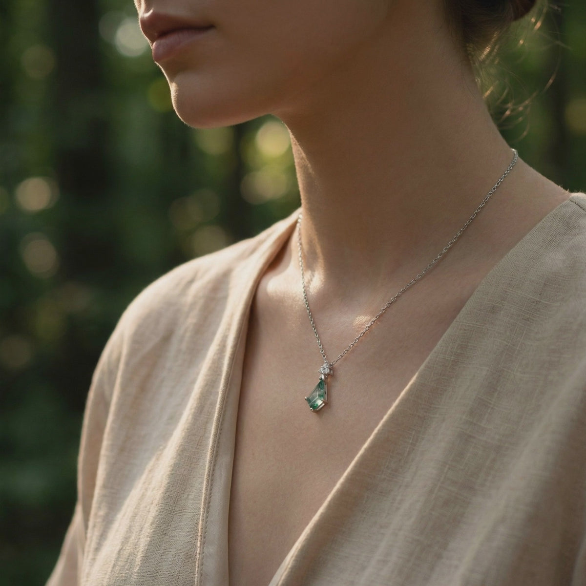 Model wearing a trillion-cut natural moss agate pendant necklace in solid white gold in soft natural light.