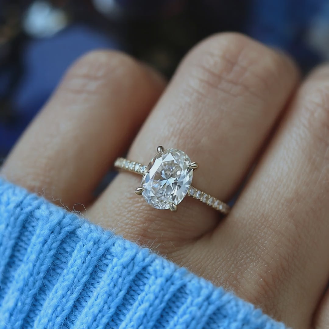 A solid gold engagement ring with an oval moissanite stone.
