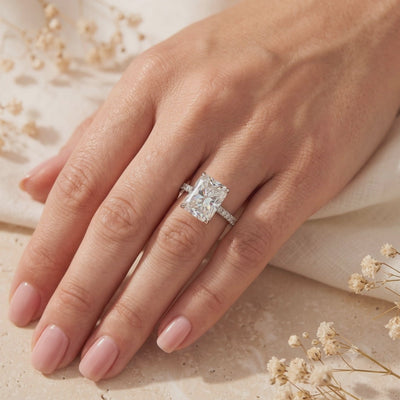 On-hand view of a silver ring with a large radiant-cut clear center stone and pavé band.