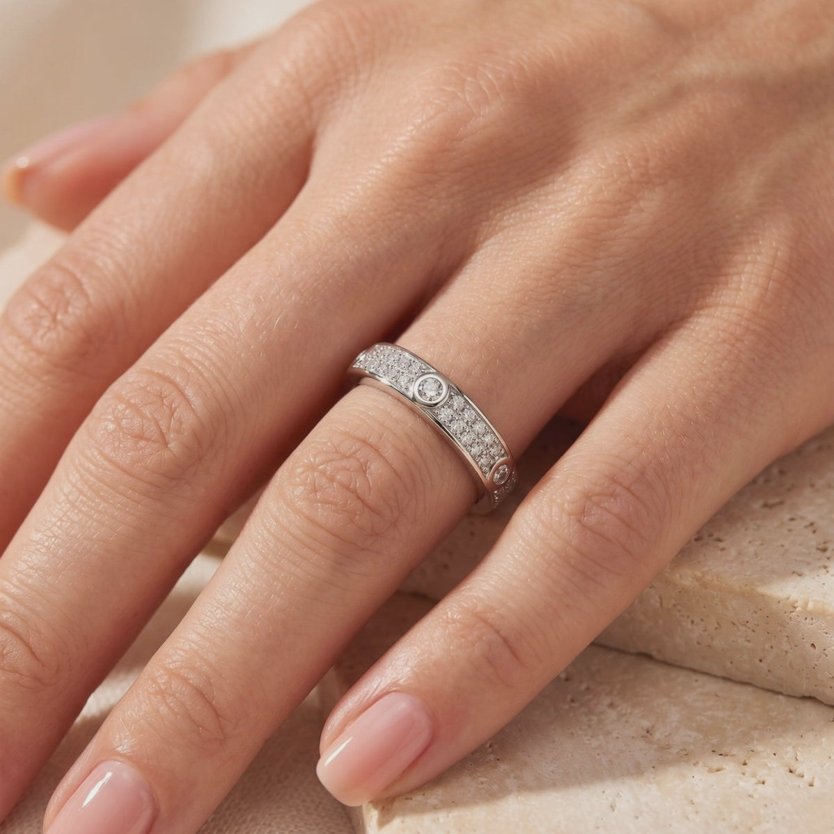 Silver ring with pavé panels and round bezel-set stones worn on a hand, shown in a close-up angled view.