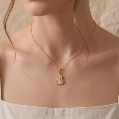 The gold-tone Sorsha necklace with a textured gourd pendant, shown worn on a model's neck.