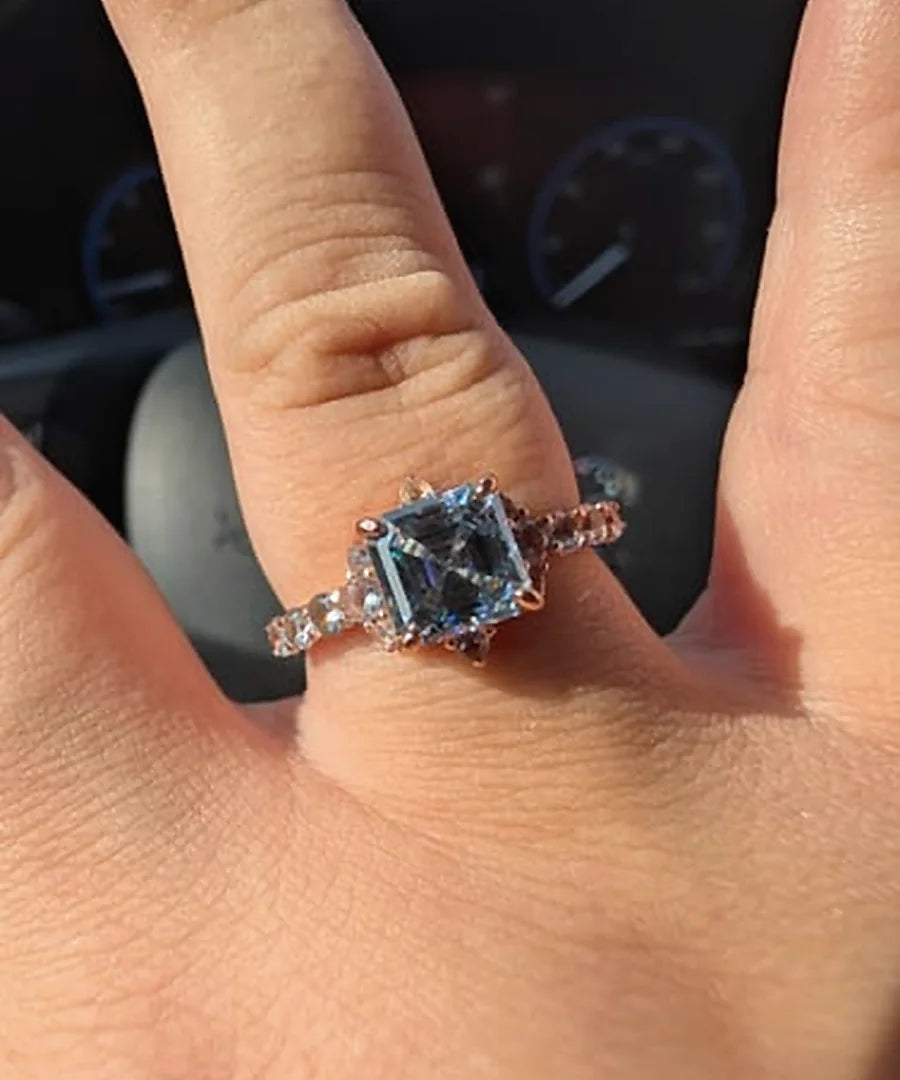 Blue emerald-cut engagement ring worn on a customer's hand