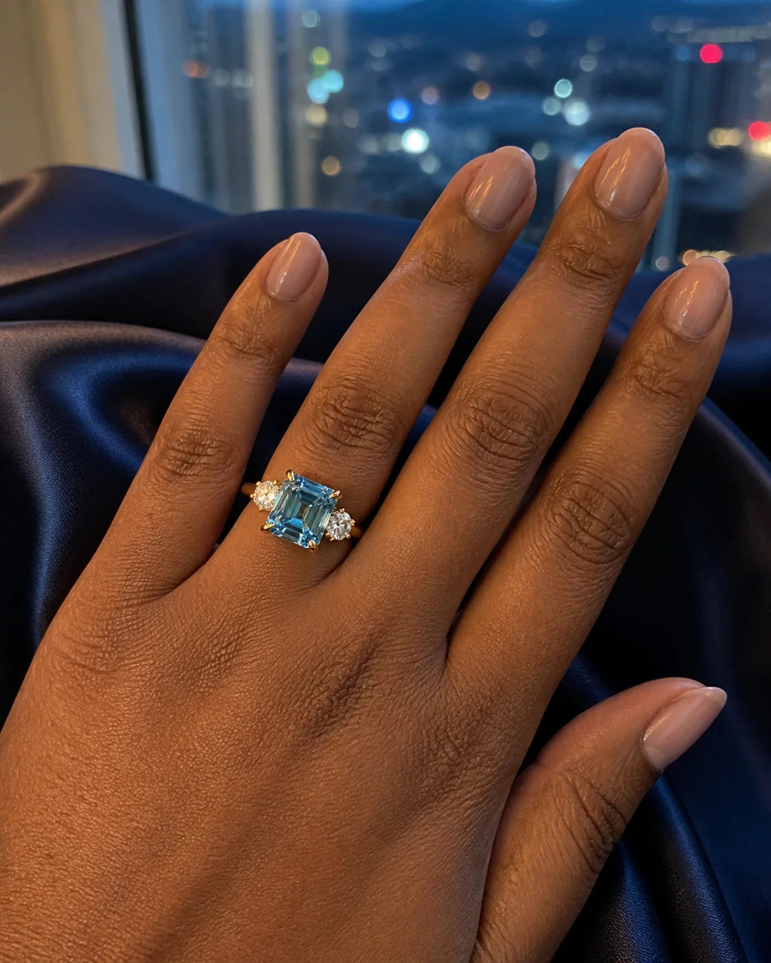 Blue emerald-cut fine-jewelry ring photographed against navy satin