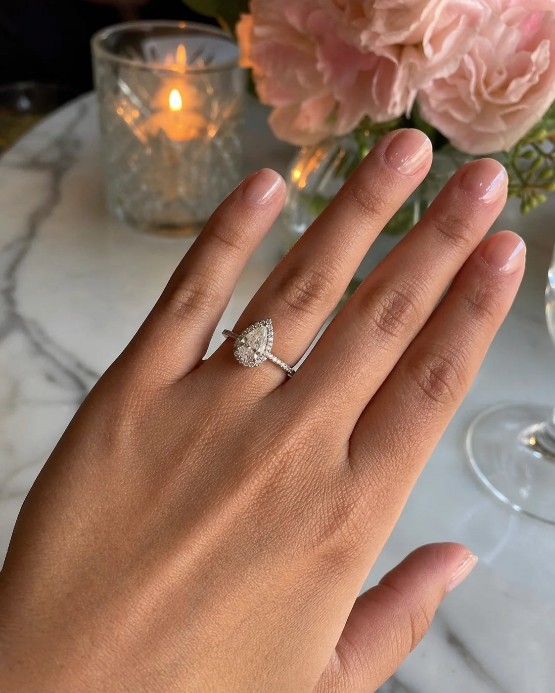 Pear-cut halo engagement ring at a celebratory dinner
