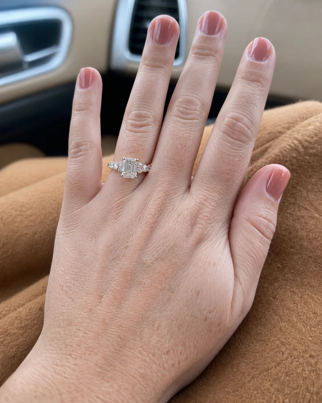 Emerald-cut three-stone fine-jewelry ring photographed in a car