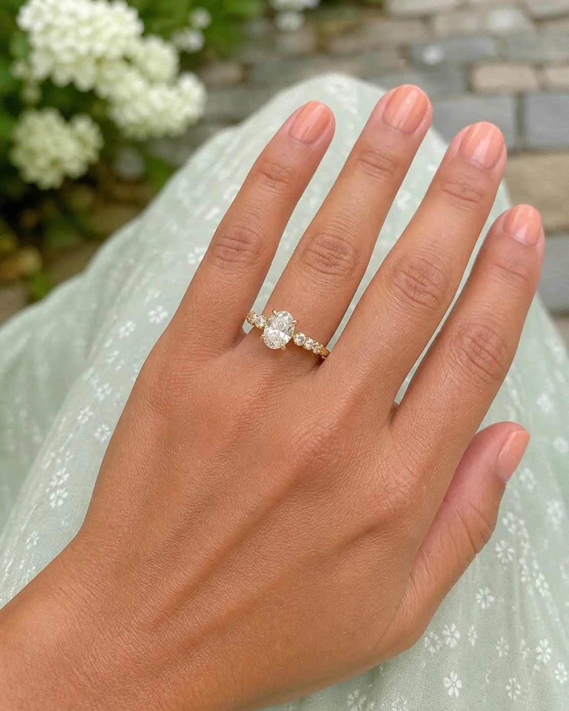 Three-stone oval fine-jewelry ring photographed in a garden